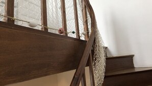 A wooden staircase with a netted barrier and a rope.
