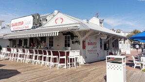 Een houten looppad met een bar genaamd 'The Shrimp Shack', met terras en uitzicht op de zee.