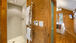 Een houten interieur met een douche, een bed en een bedieningspaneel met lichtschakelaars.