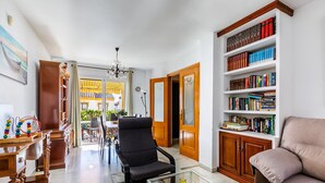 A living room with a black armchair, a glass coffee table, a beige sofa, and a bookshelf filled with books. - A&n Moriles 2      . (Torre del Mar)
