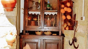Een landelijke keuken met houten kastjes, hangende potten en een stenen muur.