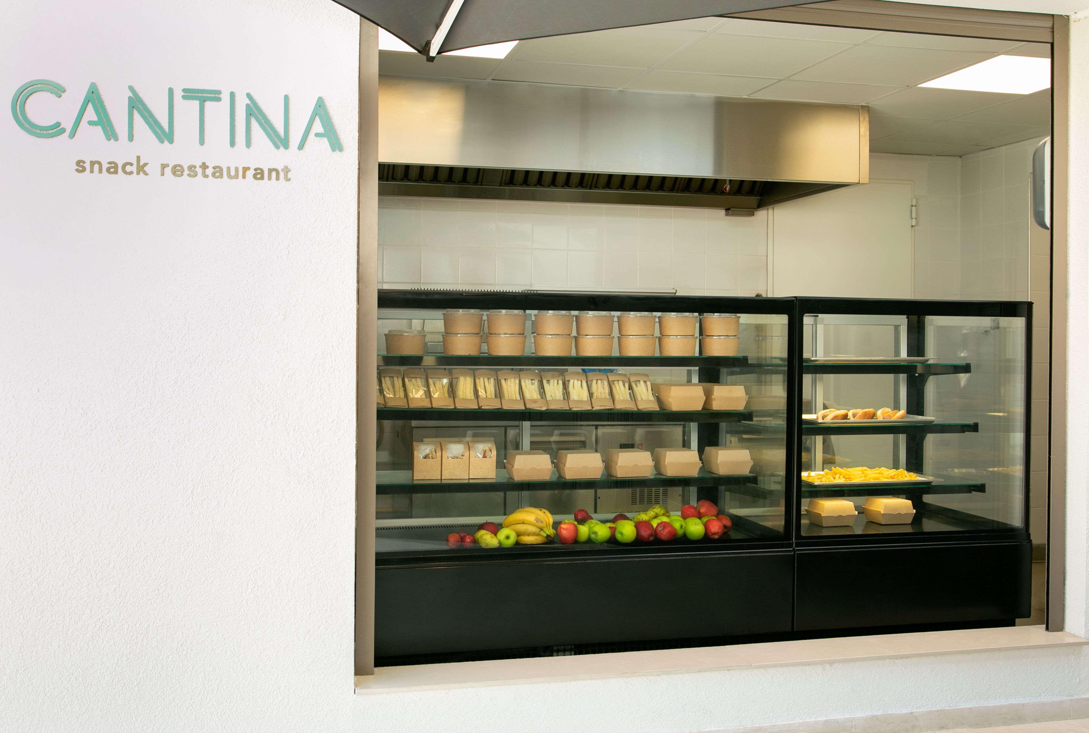 Un restaurante de aperitivos con una vitrina que contiene frutas y snacks empaquetados.