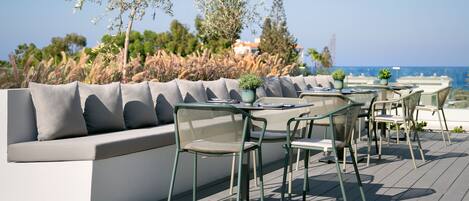 An outdoor seating area with a sofa and chairs, overlooking a beach.