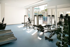 Un gimnasio con cintas de correr, mancuernas y máquinas de ejercicio.