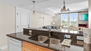 Eine moderne Küche mit Granit Arbeitsplatten, Spüle aus Edelstahl und Holzschränken.