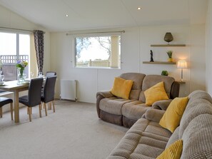 A living room with a sofa, chairs, a dining table, and a window with a view. - Ocean Glade - UK32963 (Corton, near Lowestoft)