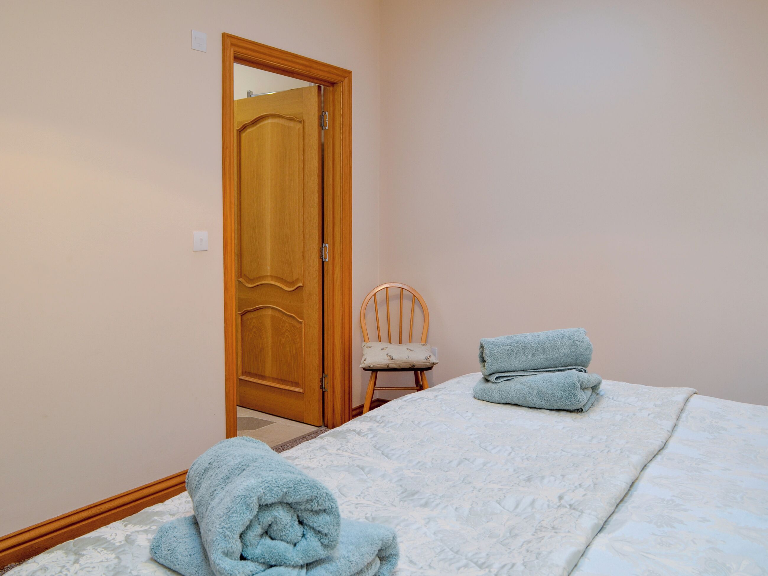 Ein Schlafzimmer mit einem Bett, einem Sessel und einer Holztür.