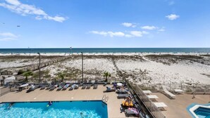 Un espace piscine situé au bord de la plage, avec des chaises longues et une vue sur la plage.