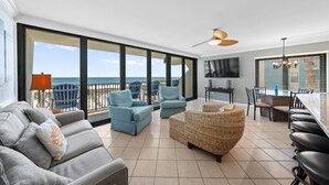 Un vaste balcon offrant une vue sur l’océan, aménagé avec un canapé, des fauteuils et une table à manger.