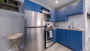 Una cocina con armarios azules, un refrigerador de acero inoxidable, un horno doble y una encimera con un fregadero.