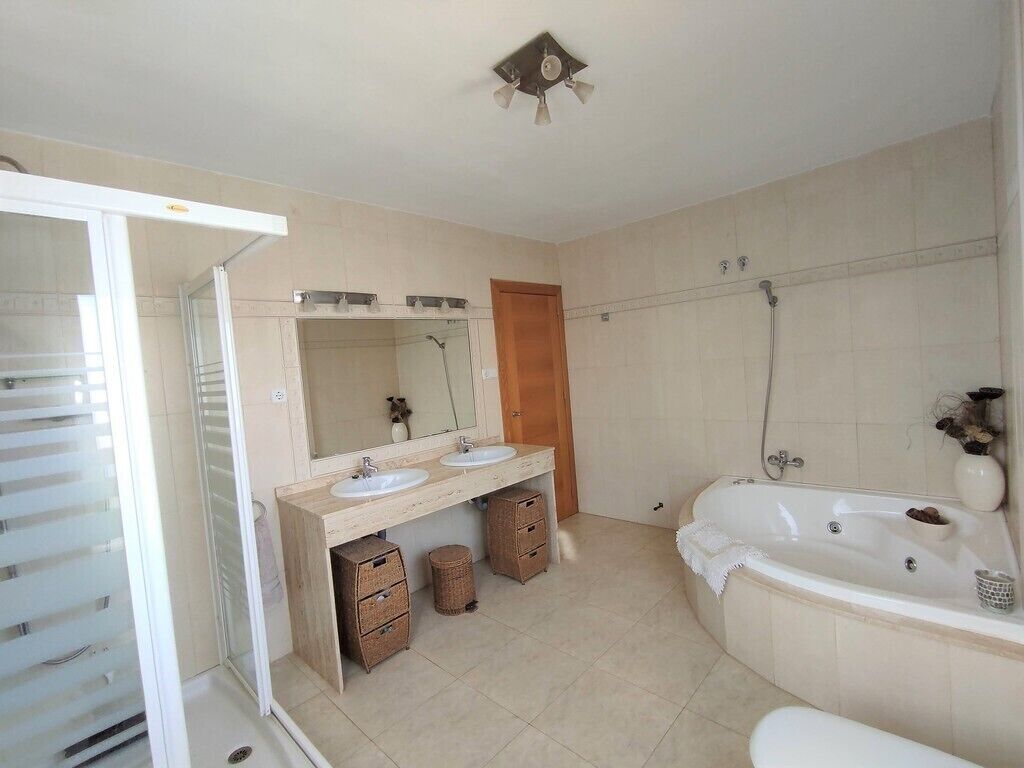 A bathroom with a shower, two sinks, a bathtub, and a mirror above the sinks.