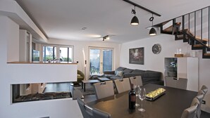 A modern living space with a dining area, a staircase, and a view of the outdoors. - House Comfort, with outdoor whirlpool and sauna for exclusive use, 300m to the lake (Göhren-Lebbin)