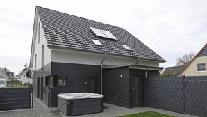 A modern house with a sloped roof, a hot tub, and a gated backyard. - House Comfort, with outdoor whirlpool and sauna for exclusive use, 300m to the lake (Göhren-Lebbin)