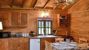 L’intérieur d’un chalet en bois comprend une cuisine, un coin repas et un canapé en cuir.