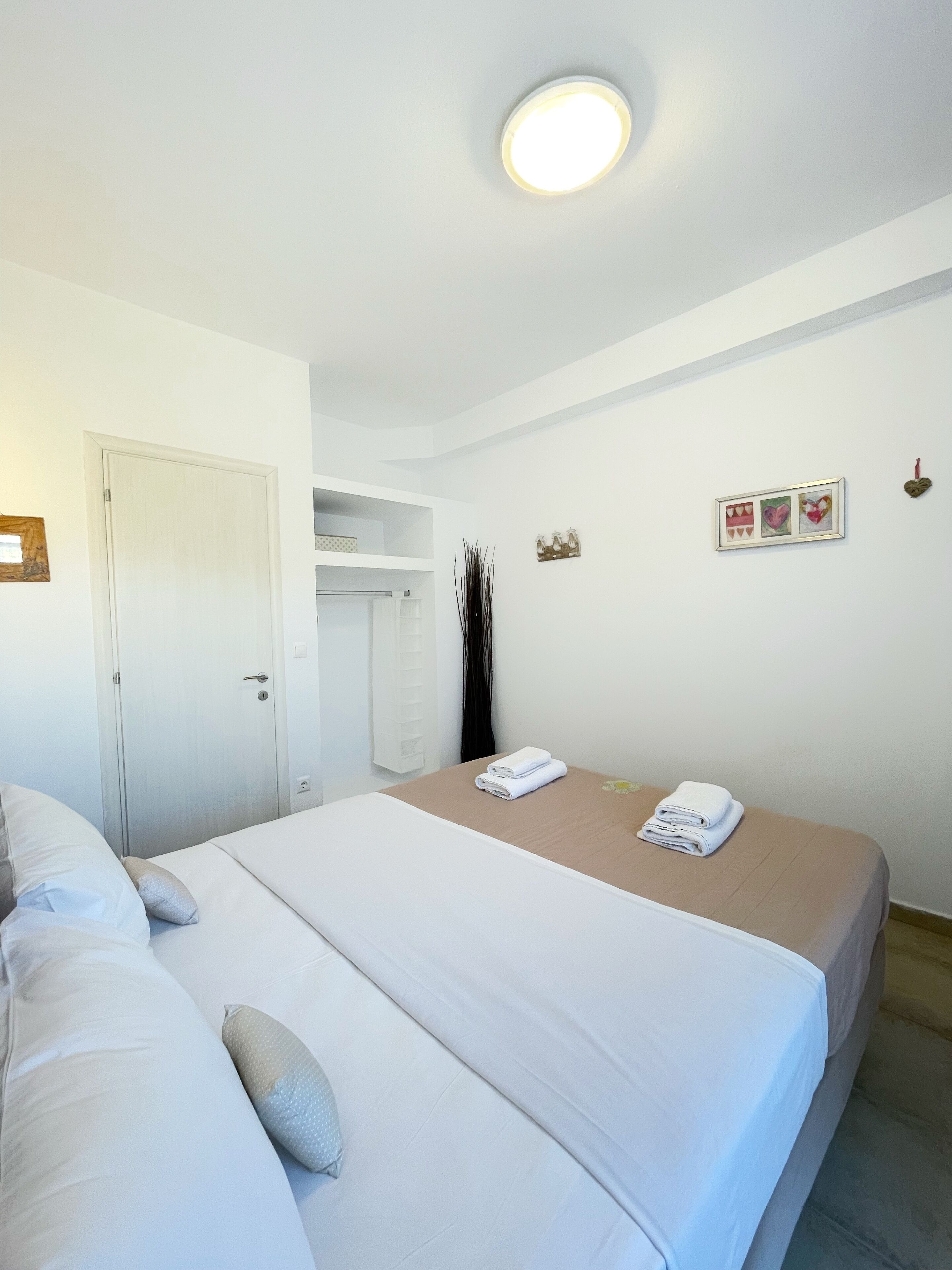 Una habitación de hotel con cama, armario y una mesita con toallas.