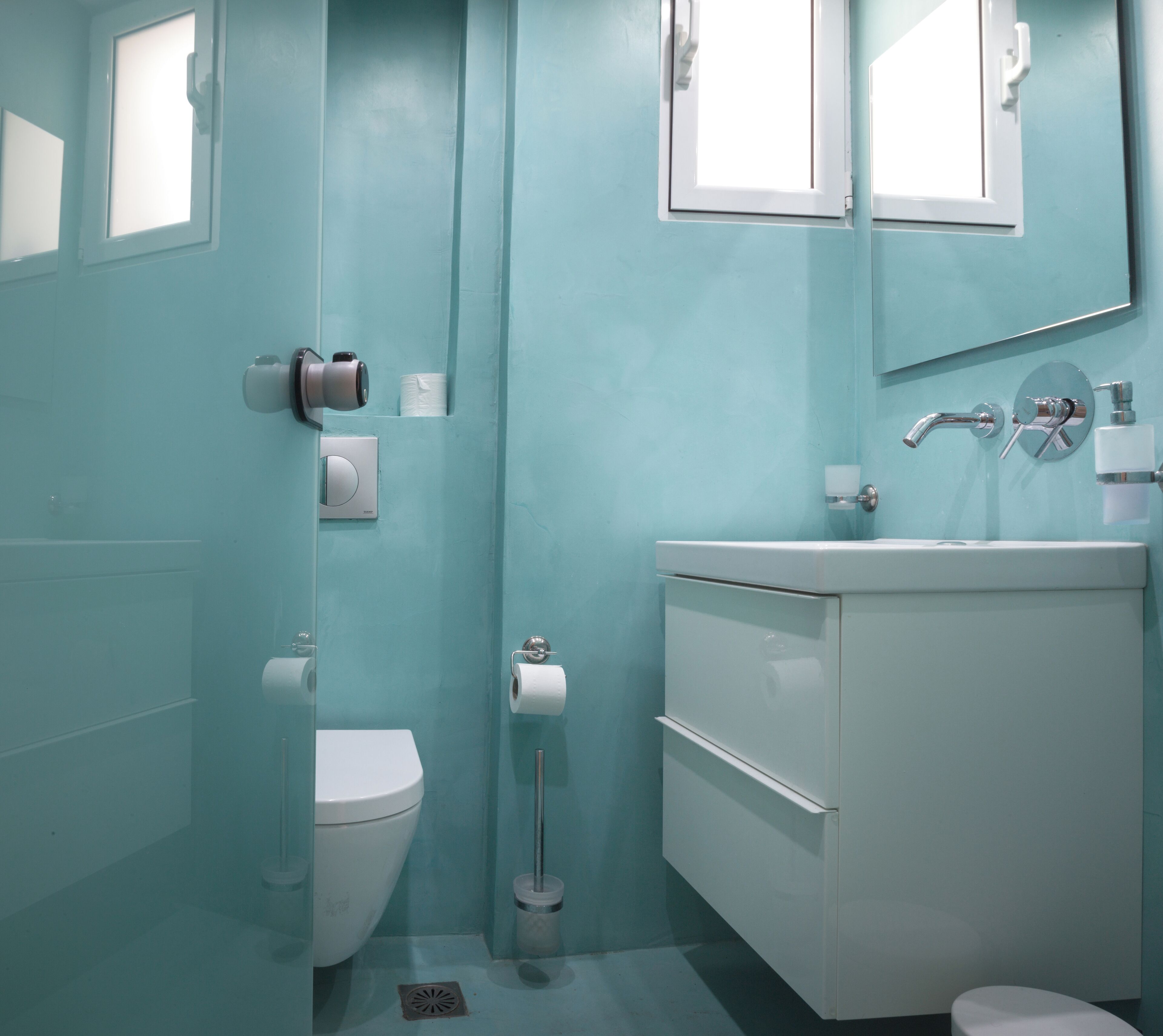 Un baño moderno con inodoro, lavamanos y espejo.
