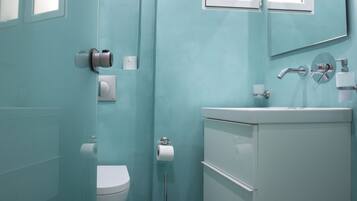 Un baño moderno con inodoro, lavamanos y espejo.