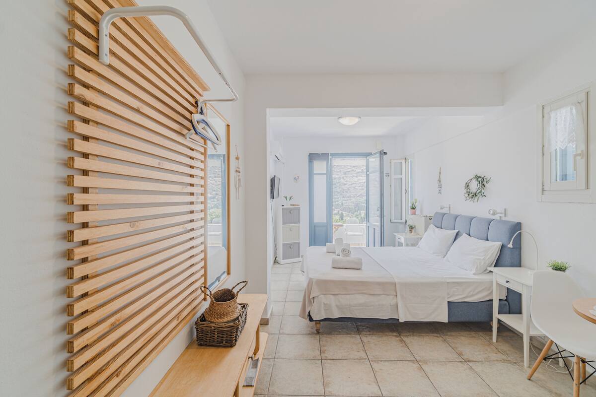 Un dormitorio con cama, mesita de noche y vistas al exterior.