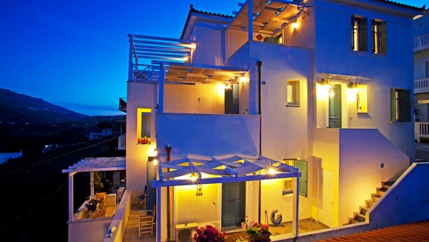 Una casa a due piani con un balcone, un'area salotto esterna e una scalinata.