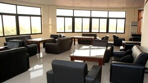 A spacious room with multiple seating arrangements, large windows, and a flat-screen TV. - K Suite Hotels (Kano)
