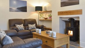 A cozy living room with a leather sofa, a wooden coffee table, a fireplace, and a scenic painting. - 2 bedroom accommodation in Skinningrove, near Saltburn-by-the-Sea (Skinningrove, near Saltburn-by-the-Sea)