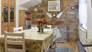 A dining area with a table set for two, a wooden cabinet, a bookshelf, and a stone wall with a painting. - 2 bedroom accommodation in Skinningrove, near Saltburn-by-the-Sea (Skinningrove, near Saltburn-by-the-Sea)