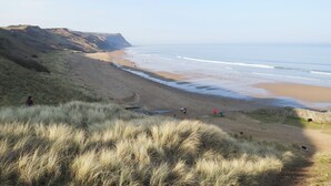 A coastal landscape with a sandy beach, grassy dunes, and a stone wall. - 2 bedroom accommodation in Skinningrove, near Saltburn-by-the-Sea (Skinningrove, near Saltburn-by-the-Sea)