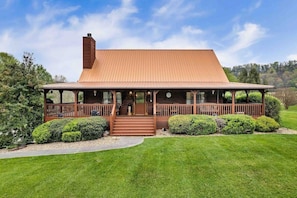 A two-story wooden house with a porch, a chimney, and a well-maintained lawn.