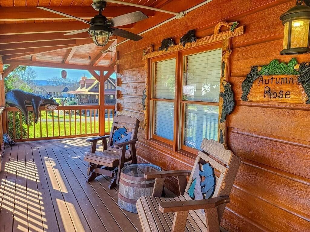Varanda de madeira com duas cadeiras Adirondack, um candeeiro e uma placa com a inscrição 'Autumn Rose'.