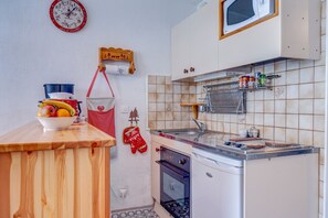 Eine kleine Küche mit Holzarbeitsplatte, Spüle, Herd und Mikrowelle.