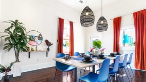 Un comedor con una mesa de madera, sillas azules y cortinas rojas.
