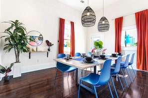 A dining area with a wooden table, blue chairs, and red curtains.