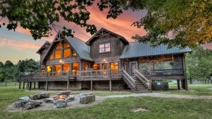 A rustic lodge with a large deck, a fire pit, and a prominent signboard. - The Haven on Toccoa - River deck | Fire Pit | Hot Tub | Outdoor Fireplace (Blue Ridge)