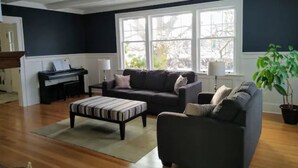 A living room with a piano, a sofa, a loveseat, and a striped ottoman. - Updated Heritage House close to Naramata Bench (Penticton)