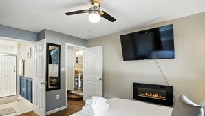 Une chambre d’hôtel équipée d’un lit, d’un téléviseur fixé au mur, d’une cheminée et d’un ventilateur de plafond.