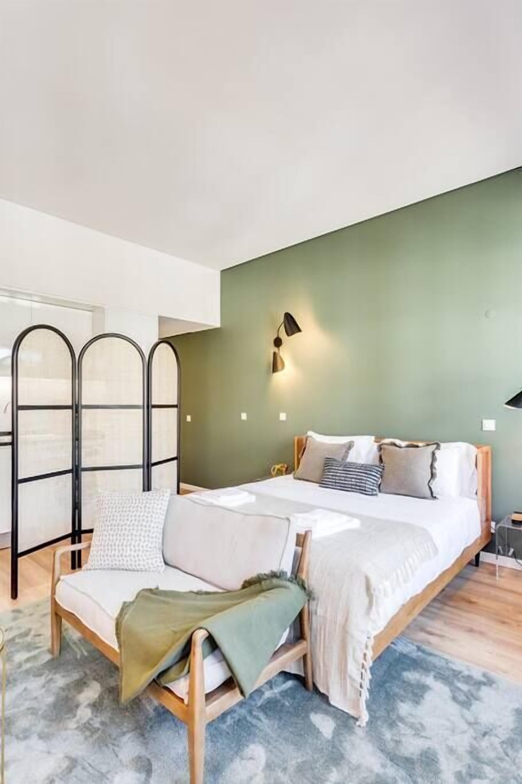 A bedroom with a bed, bedside tables, a nightstand, a window, and a view of the outside.