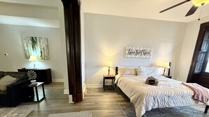 A bedroom with a large bed, two bedside tables, a nightstand, a wall-mounted artwork, and a ceiling fan. - Large 1BR on hill close to everything in Pitt (Pittsburgh)