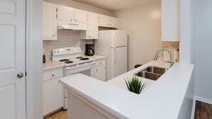 A modern kitchen with white cabinetry, a built-in stove, a refrigerator, and a sink. - Patriots Point a Stylishly decorated duplex -Near MCAS Cherry Point– VERY CLEAN! (Havelock)