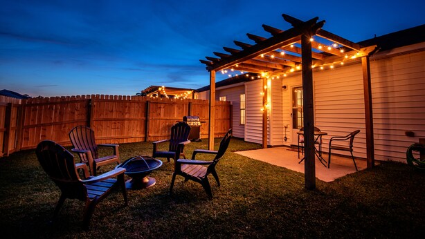 A backyard with a wooden pergola, string lights, and outdoor furniture. - Patriots Point a Stylishly decorated duplex -Near MCAS Cherry Point– VERY CLEAN! (Havelock)
