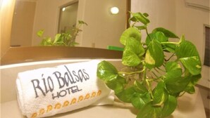 A hotel towel with "Rio Bodas Hotel" printed on it, placed on a counter next to a green plant. - Hotel Rio Balsas (Manzanillo)