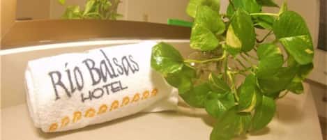 A hotel towel with "Rio Bodas Hotel" printed on it, placed on a counter next to a green plant.