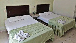 Two twin beds with green bedspreads, a small bedside table with a plant, and a wall-mounted light fixture. - Hotel Rio Balsas (Manzanillo)