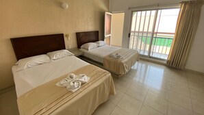 A hotel room with two beds, a sliding glass door to a balcony, and a plain wall. - Hotel Rio Balsas (Manzanillo)