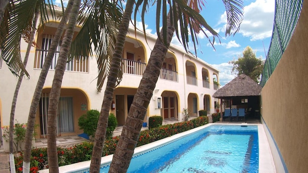 A swimming pool surrounded by palm trees and a building with arched windows and balconies. - Hotel Rio Balsas (Manzanillo)