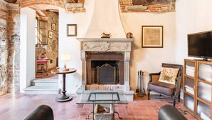 A cozy living room with a fireplace, stone walls, and rustic wooden beams. - Villa Pera by Nicola Real Estate (Corsanico)