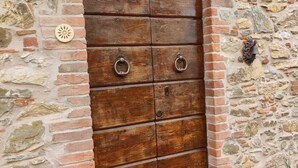 A wooden door with two round metal handles, set in a stone wall with a brick arch above it. - Villa Pera by Nicola Real Estate (Corsanico)