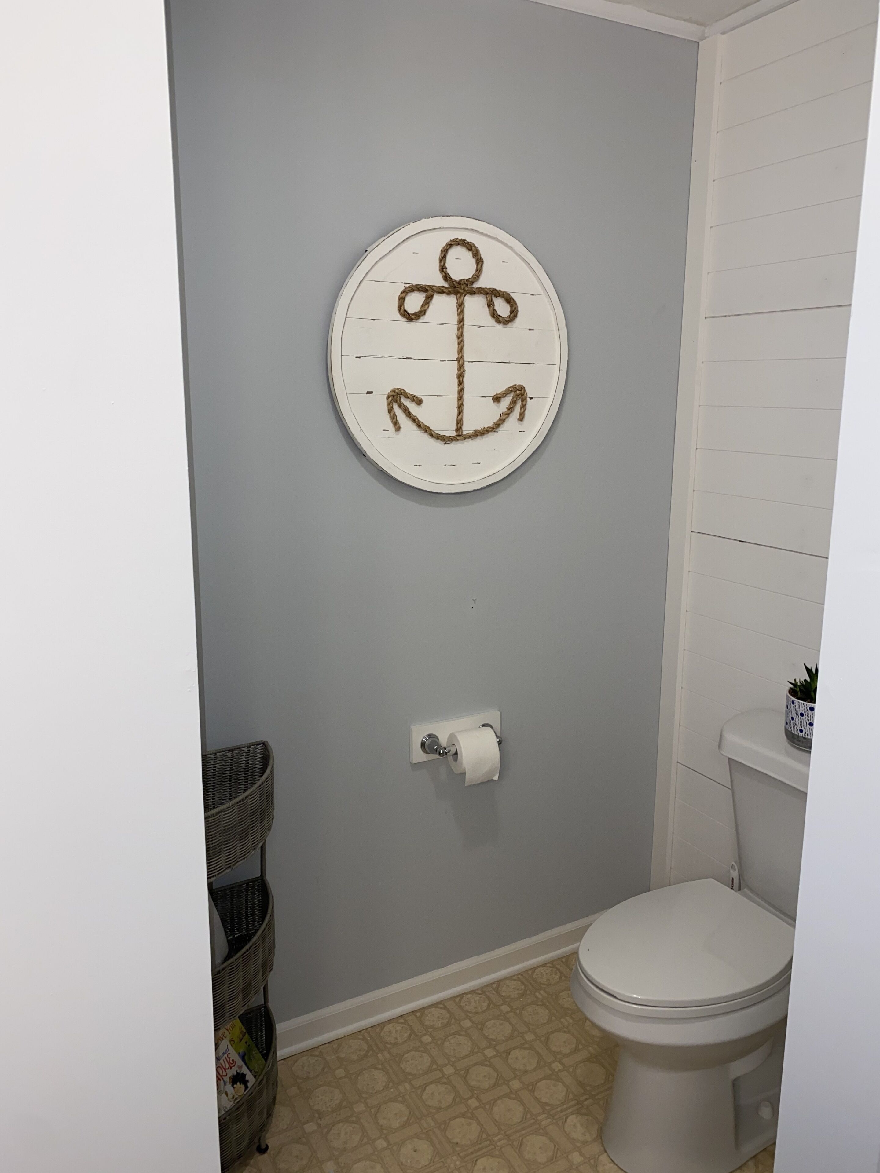 Un bagno con un water, un portasciugamani montato a parete e un ancora decorativa al muro.