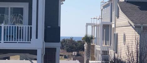 Un immeuble résidentiel à plusieurs étages, doté d’un balcon, d’une entrée sécurisée et offrant une vue sur la mer en arrière-plan.