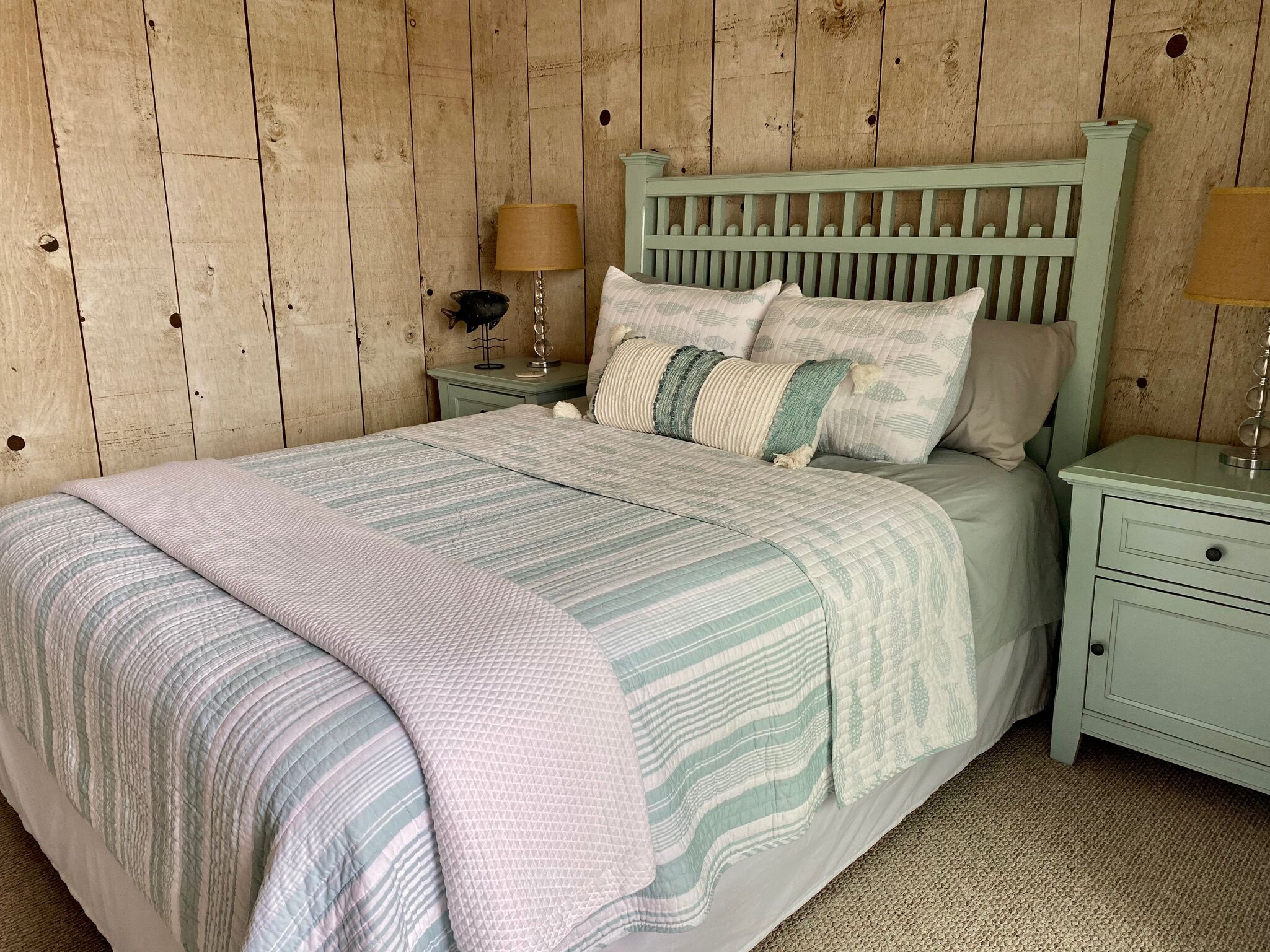 Ein Schlafzimmer mit einem Bett, Nachttischen und einer Holzwand.