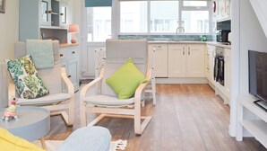 A modern living room with a sofa, chairs, a small table, and a television. - Sanderling - UK32837 (Freshwater East, near Pembroke)